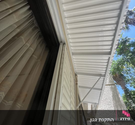 סוכך מתכת לבן מחובר לקיר חיצוני